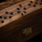 Zoom macro sur le couvercle d'une boîte support d'encens en bois, sur fond noir.