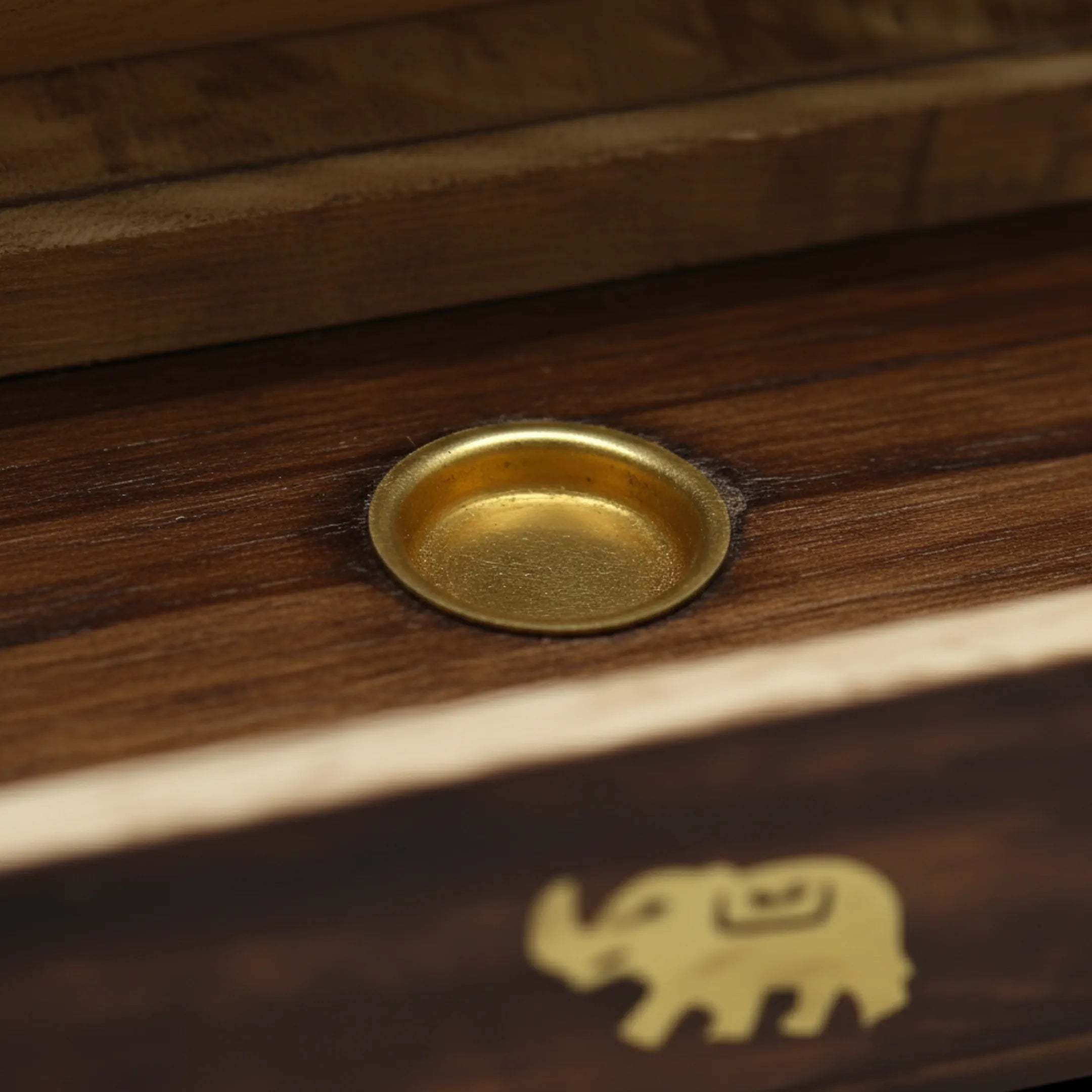 Zoom macro sur un des deux supports à cônes d'encens, d'une boîte en bois support d'encens, sur fond noir.