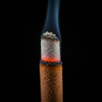 Bâtonnets d'encens Nag Champa de la marque Satya, en train de brûler, en vue macro, sur fond noir.