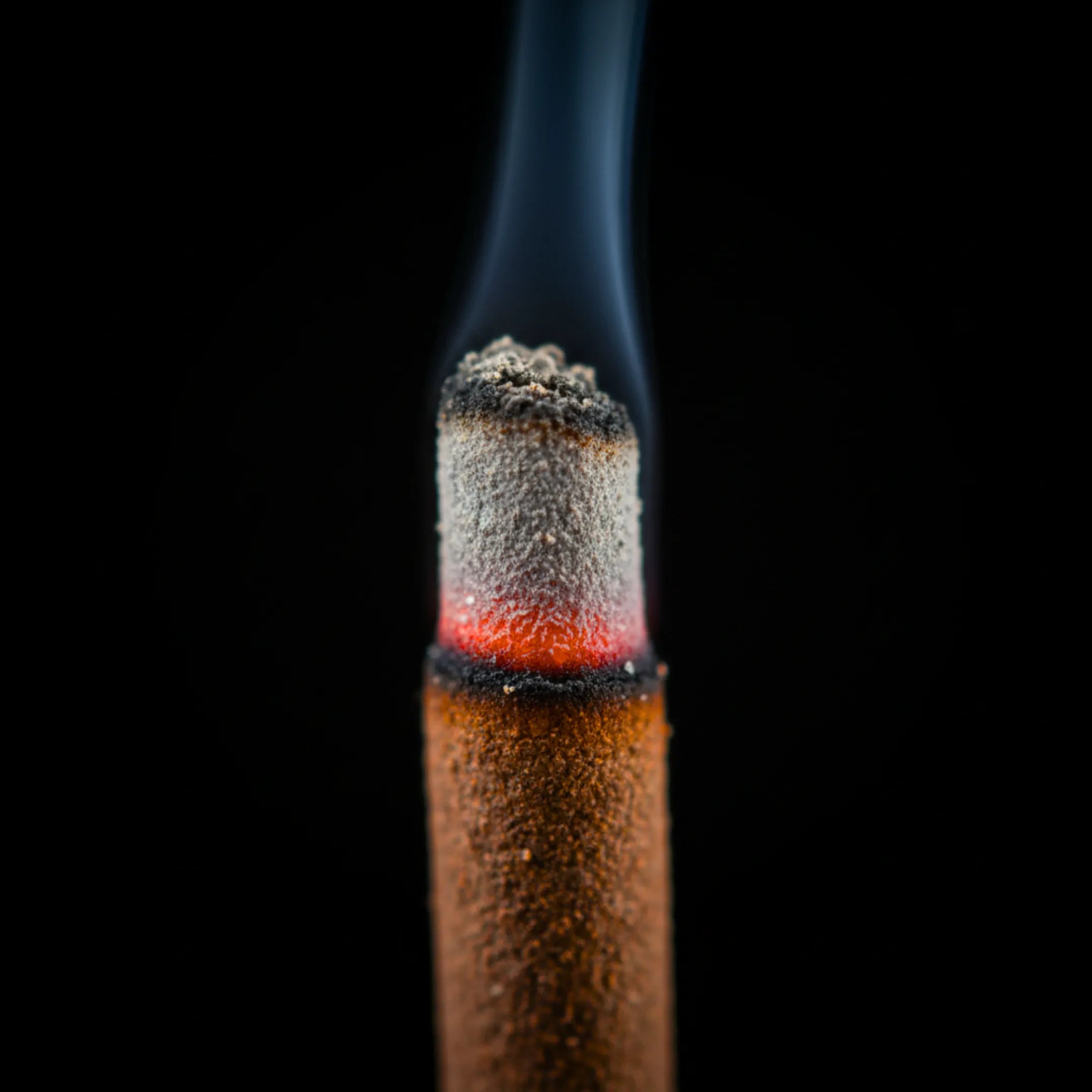 Bâtonnets d'encens Nag Champa de la marque Satya, en train de brûler, en vue macro, sur fond noir.