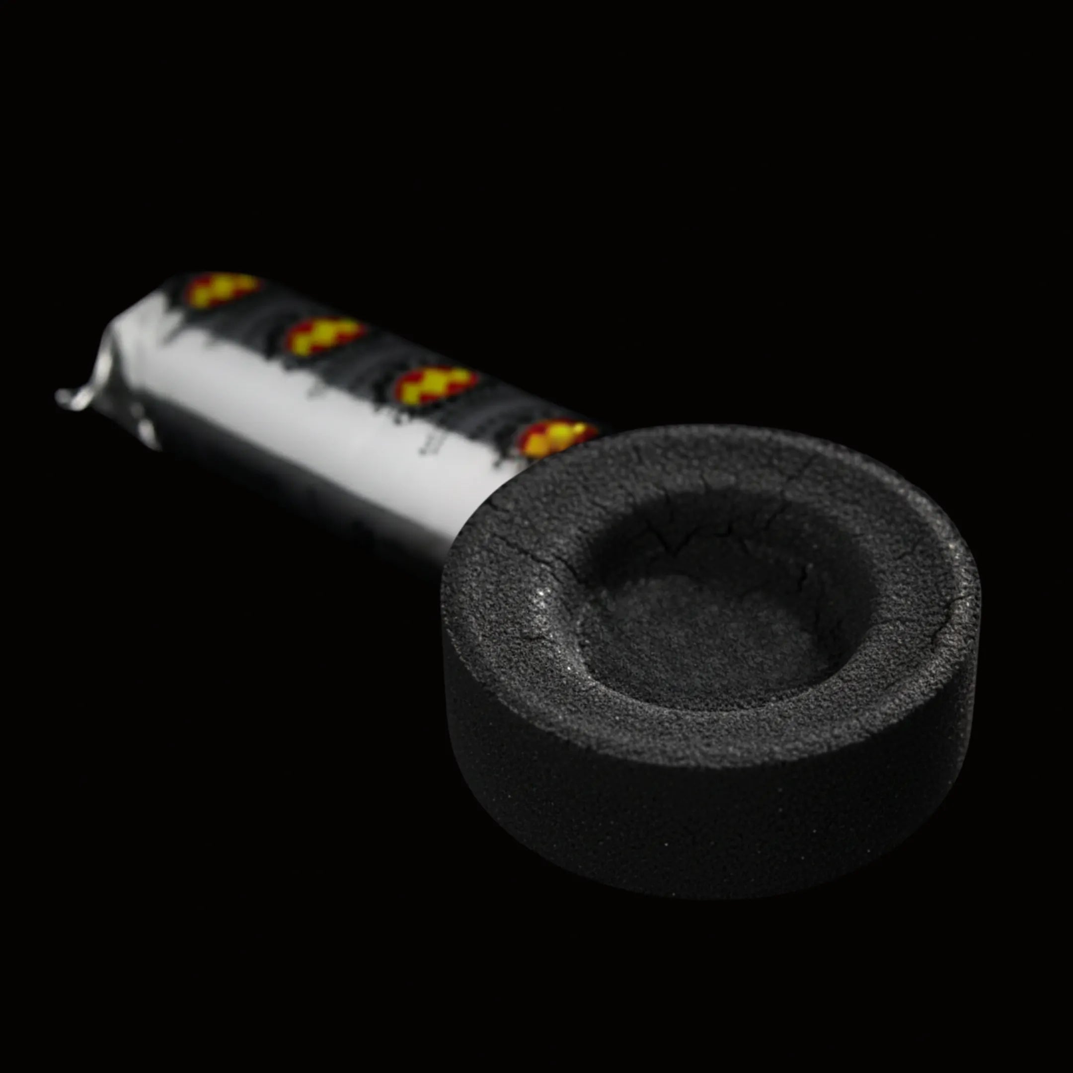 Palet de charbon ardent vu de face avec son emballage de la marque Swift Lite en arrière plan, le tout sur fond noir.