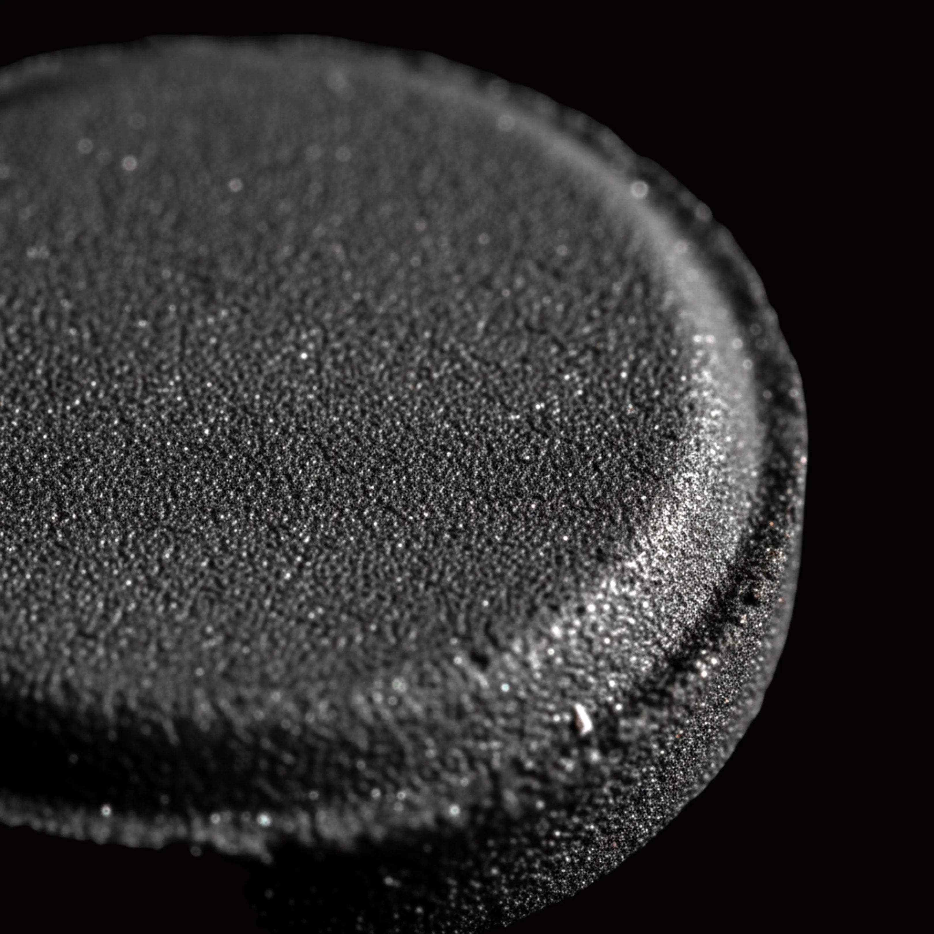 Palet de charbon ardent vu en macro sur fond noir.